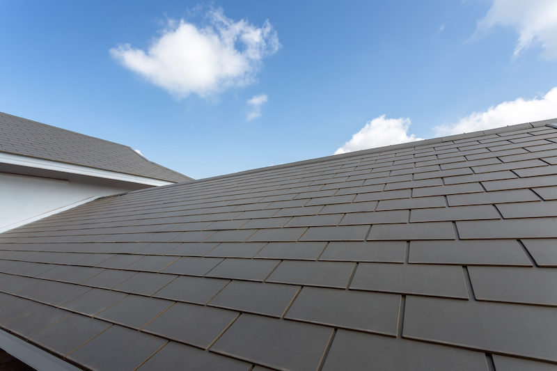 Slate roof against blue sky, Gray tile roof of construction house with blue sky and cloud background